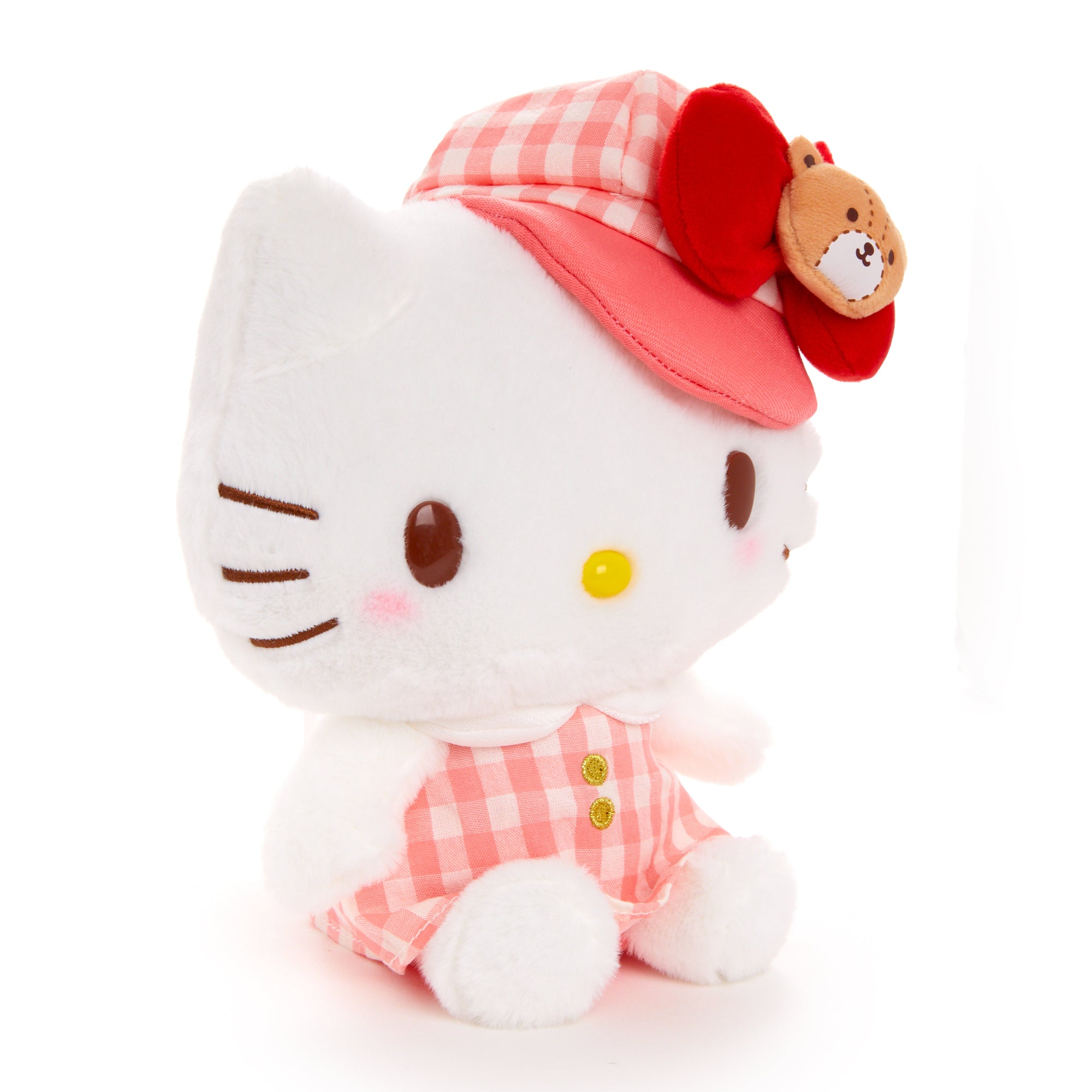 Front-facing Hello Kitty plush wearing a gingham cap, placed near study books.