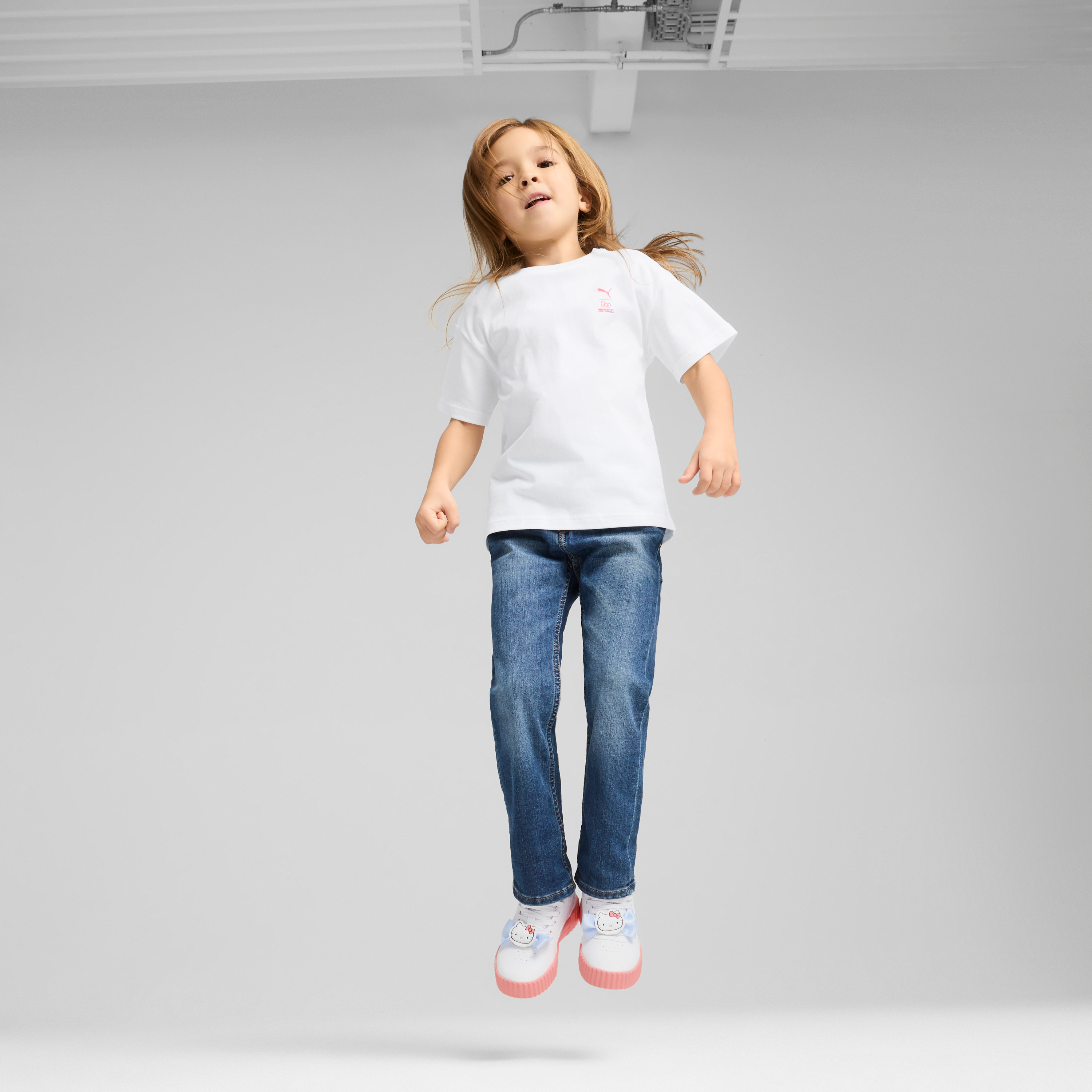 Back view showing playful graphics on graphic tee for girls with beach skateboard in hand
