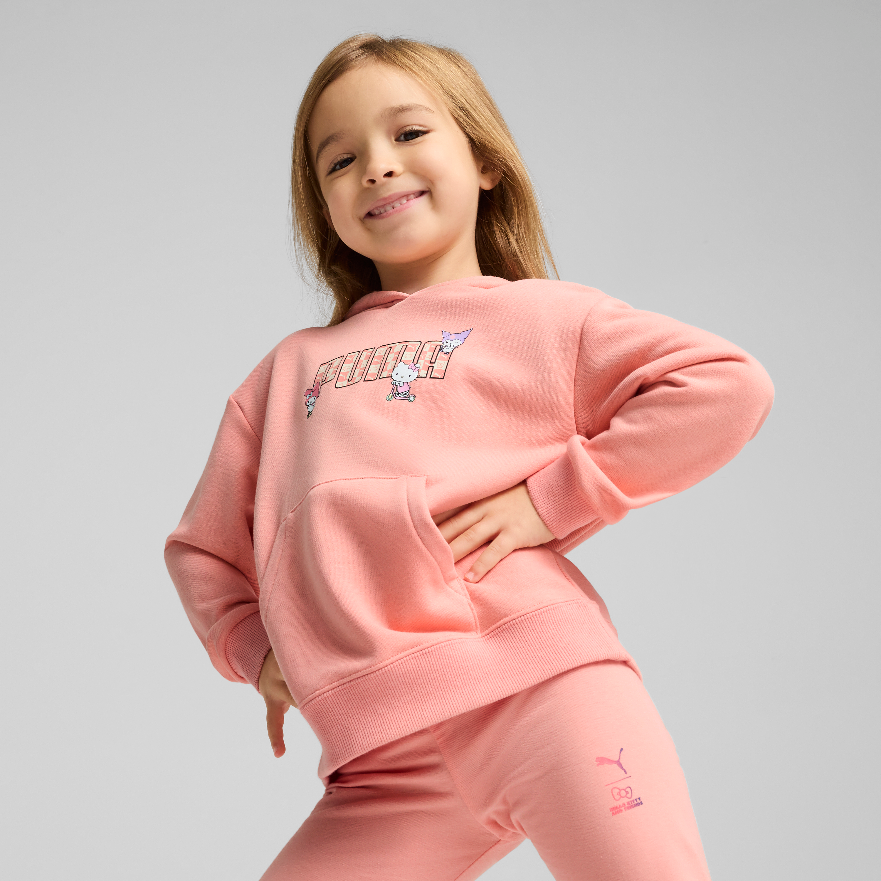 Child wearing PUMA x Hello Kitty pink hoodie in a playful setting