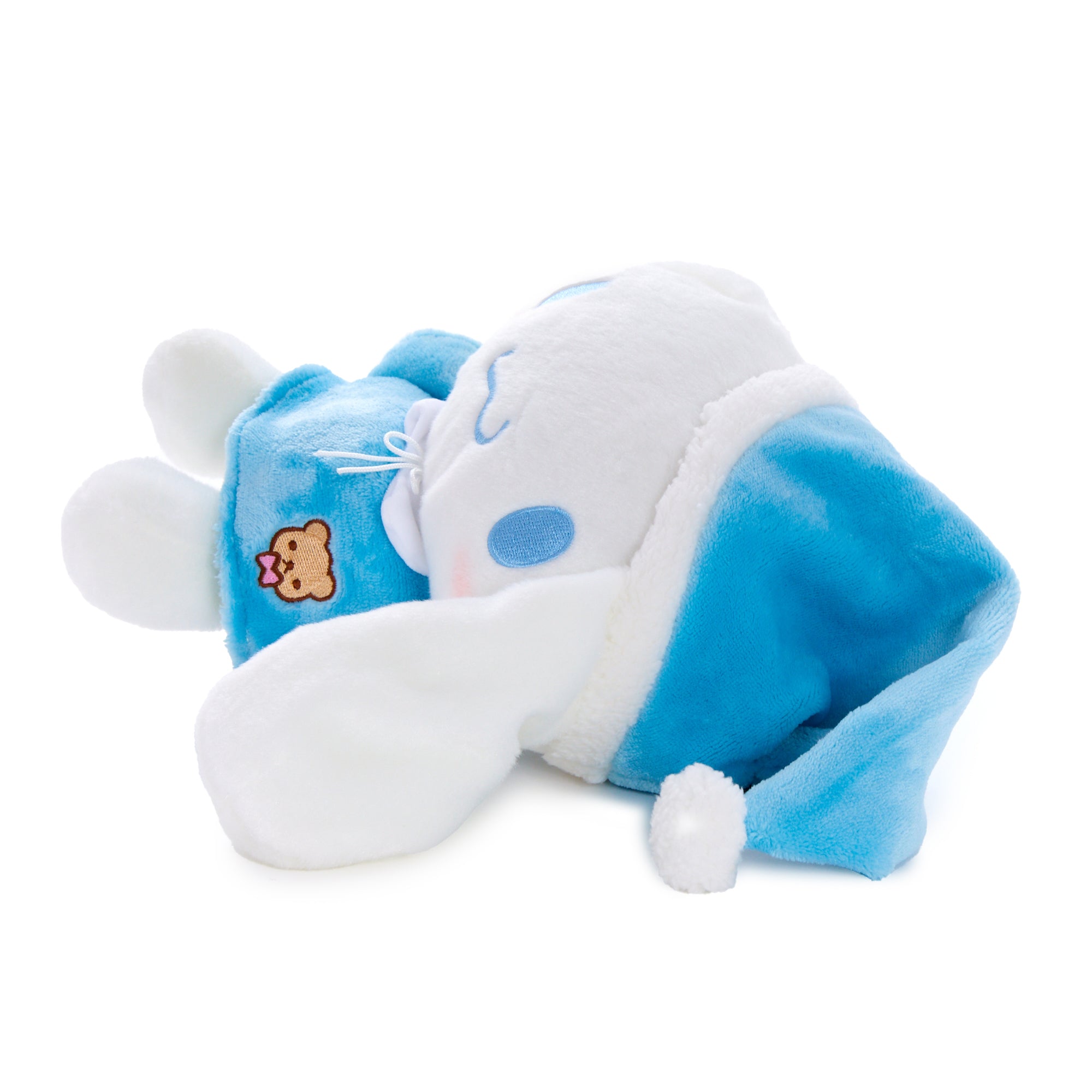 Cinnamoroll plush toy lying on a bed with pillows, ready for sleep
