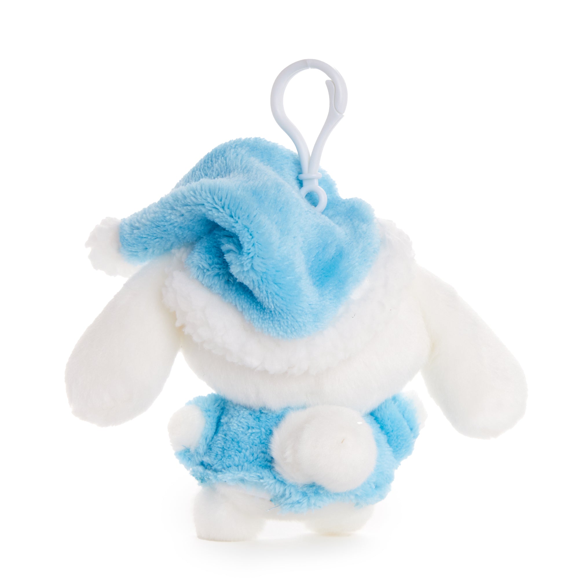 Cute keychain plush of cinnamoroll posed next to bedtime accessories on a nightstand