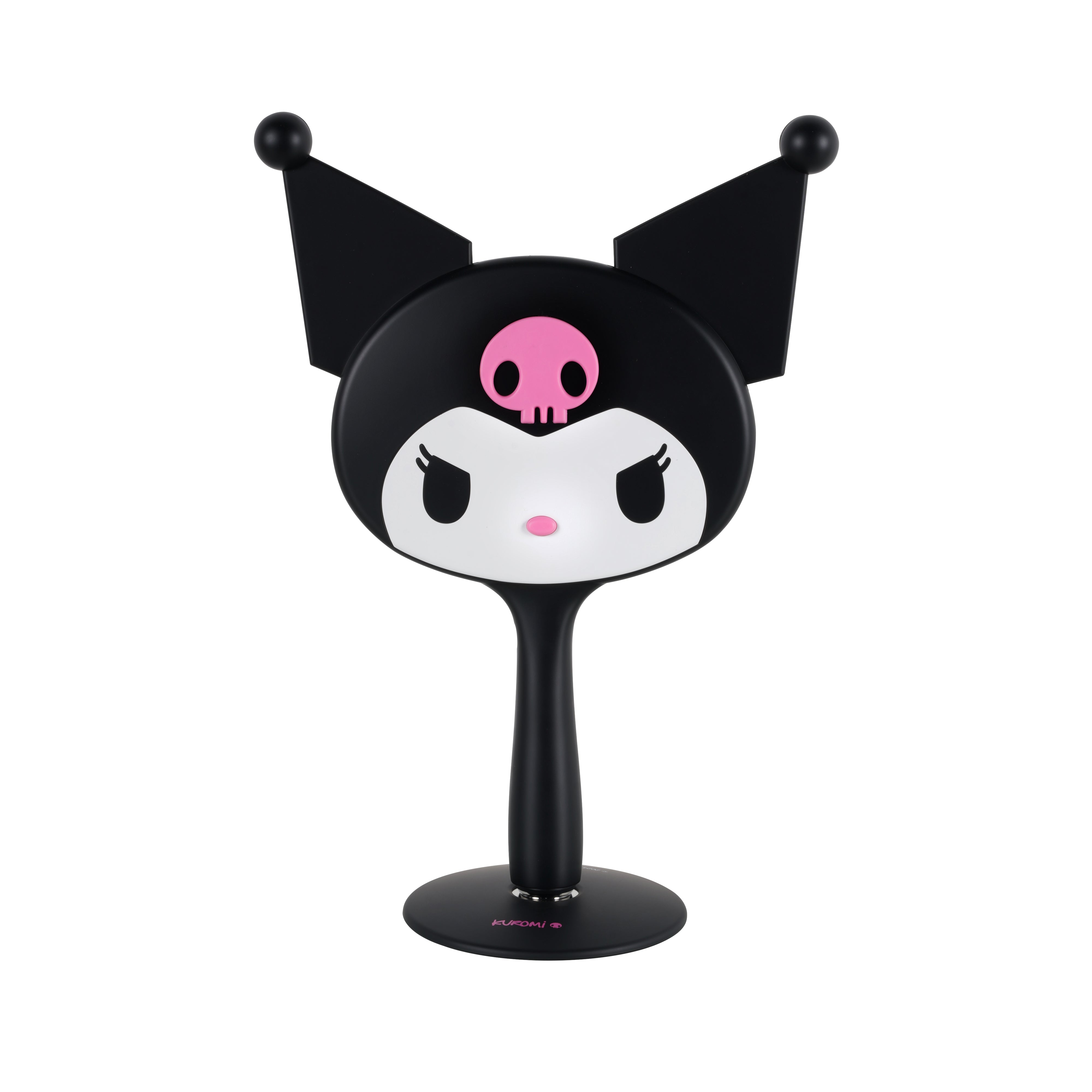 A top-down view of the Kuromi LED handheld mirror placed beside a makeup vanity setup