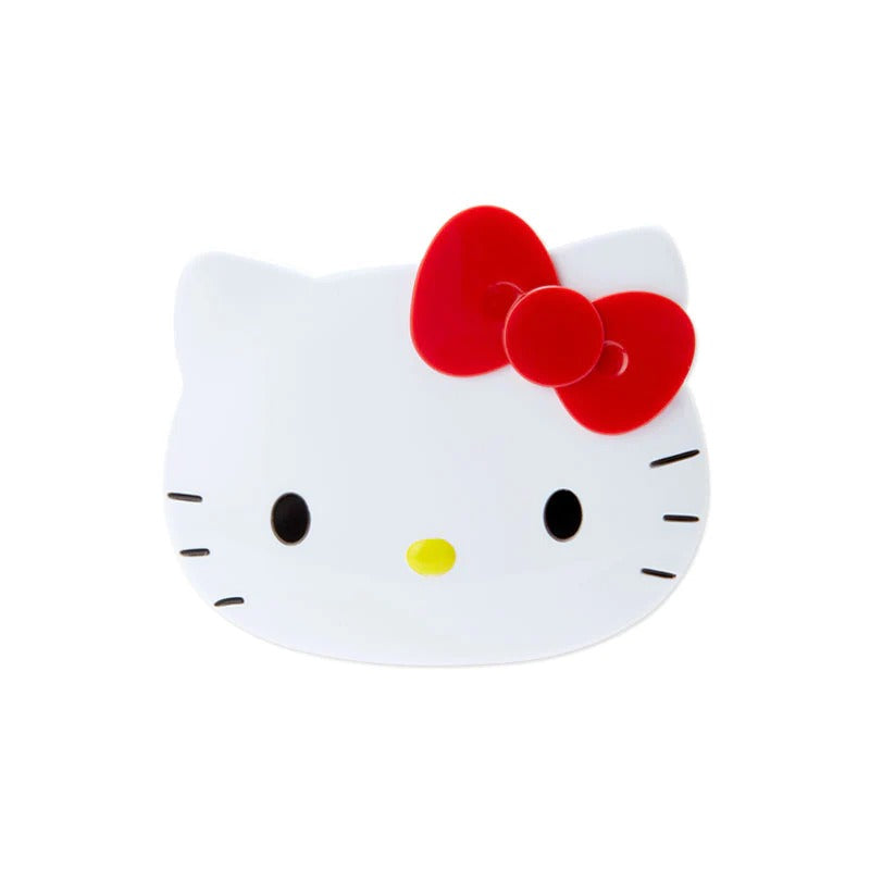 Hello Kitty compact mirror open with mini comb, resting on a pink purse