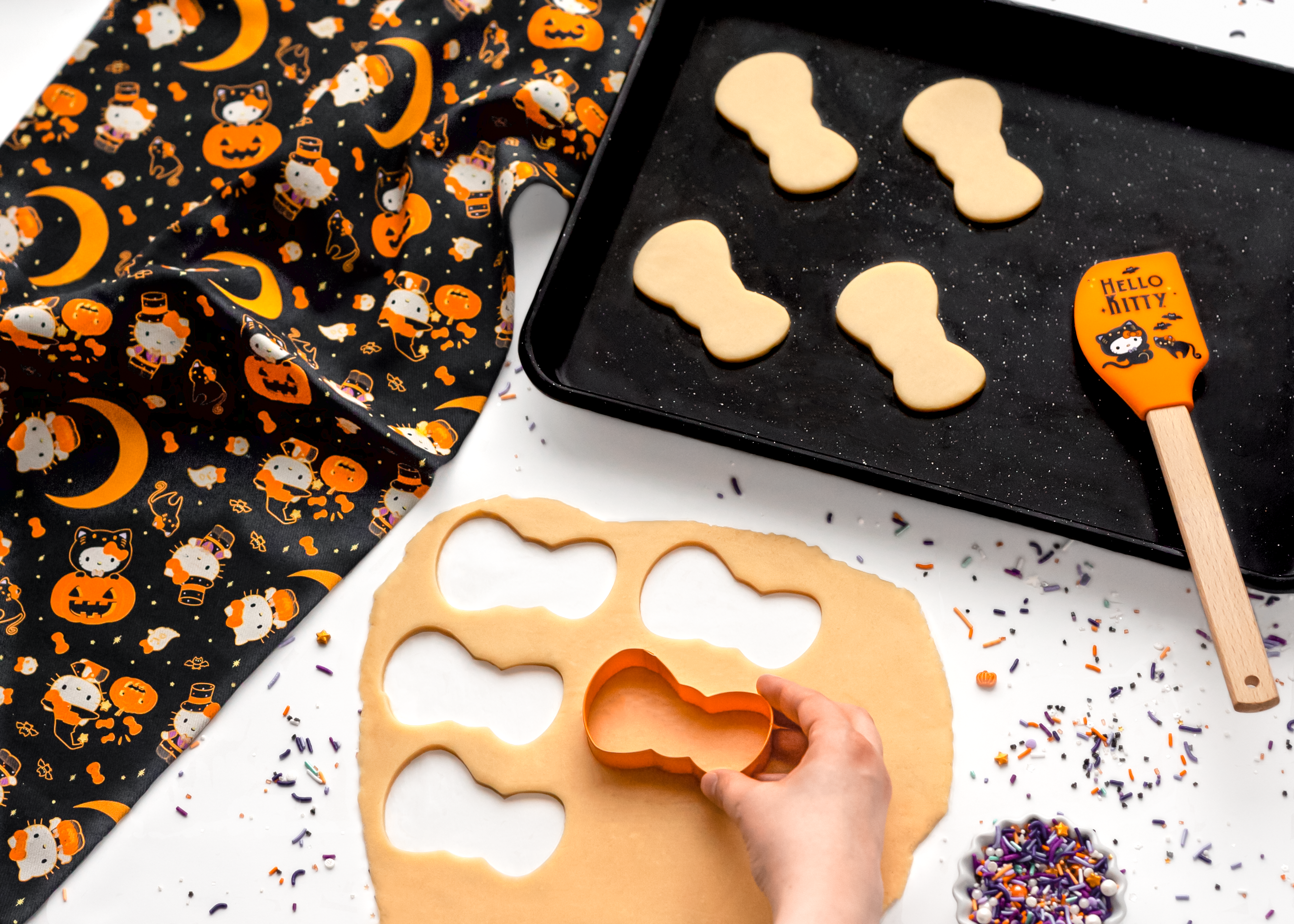 Silicone spatula with colorful print beside freshly cut cookie shapes
