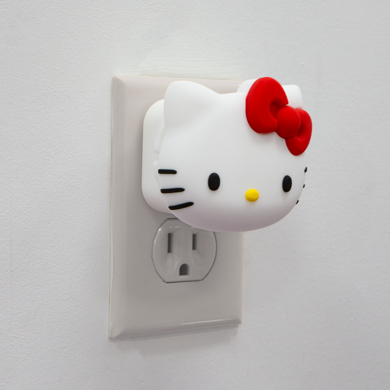 Hello Kitty USB wall adapter plugged into an outlet, showcasing the 3D silicone face cover.