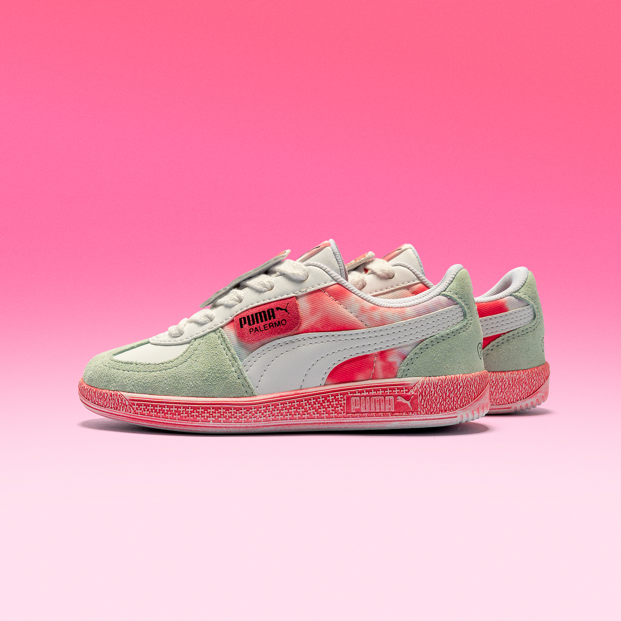 Hello Kitty PUMA Palermo shoes displayed on a beach towel, showcasing vibrant tie-dye details
