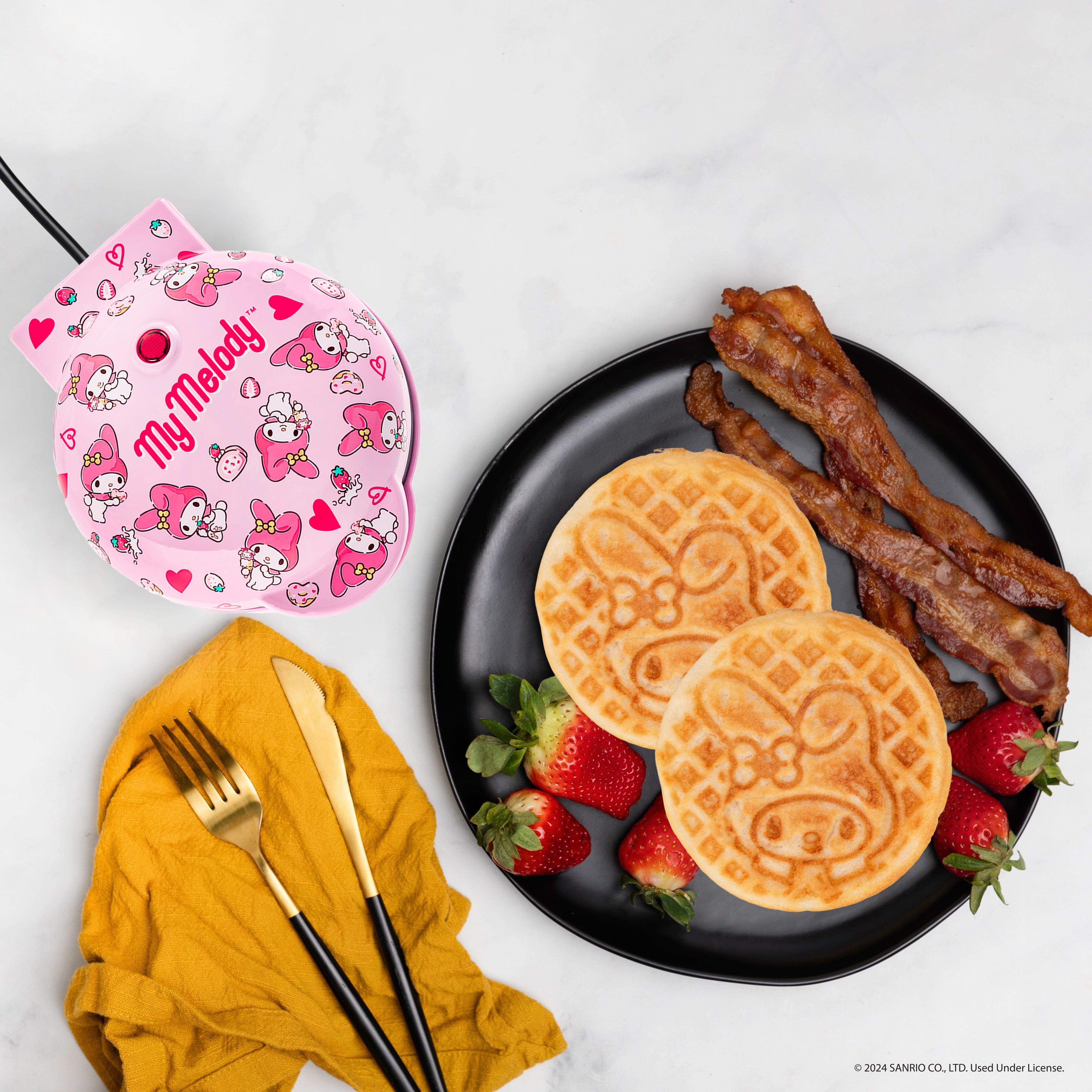 Cute waffle maker displayed on a kitchen counter with plated waffles beside it.