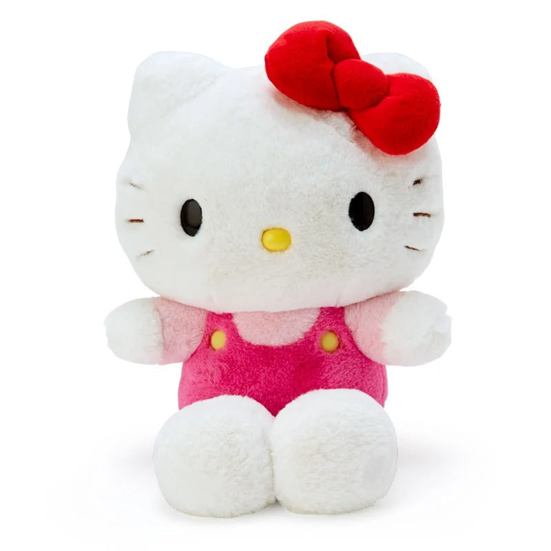 Front angle of hello kitty stuffed animal in baby blush overalls on a shelf