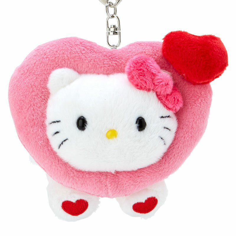 Hello Kitty mascot clipped onto a canvas backpack at a school bus stop.
