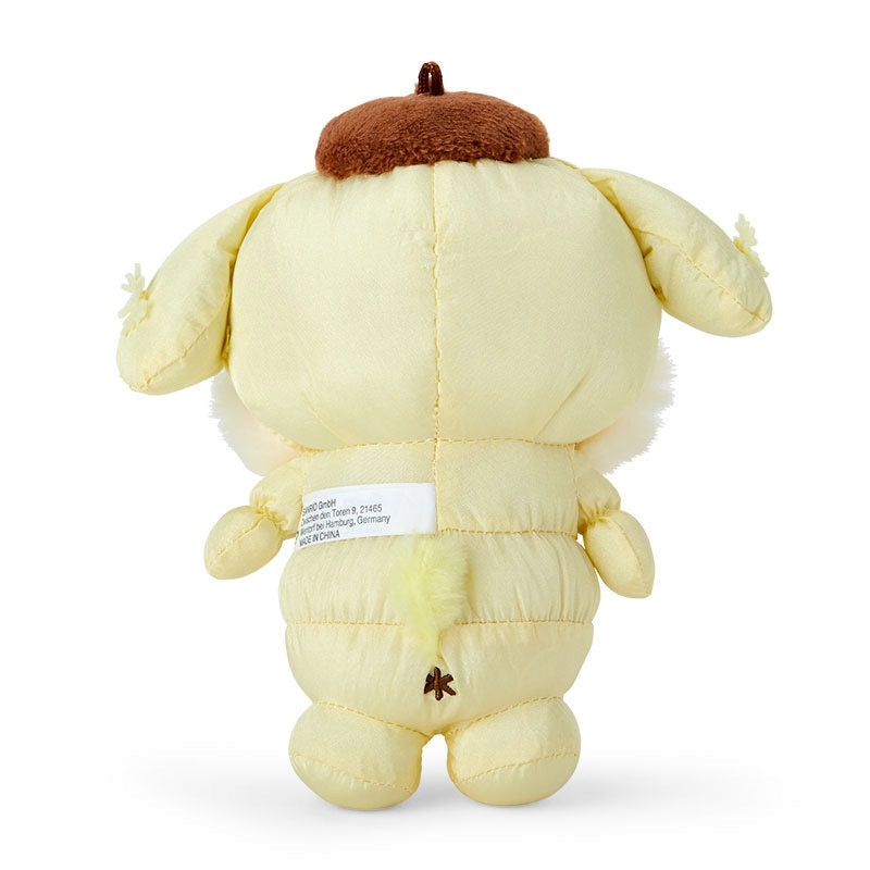 Top-down image of the plush mascot keychain attached to a backpack on a snowy walk