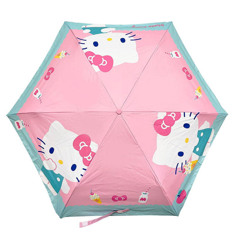 Open Hello Kitty foldable umbrella with sweet treats print against a city backdrop.