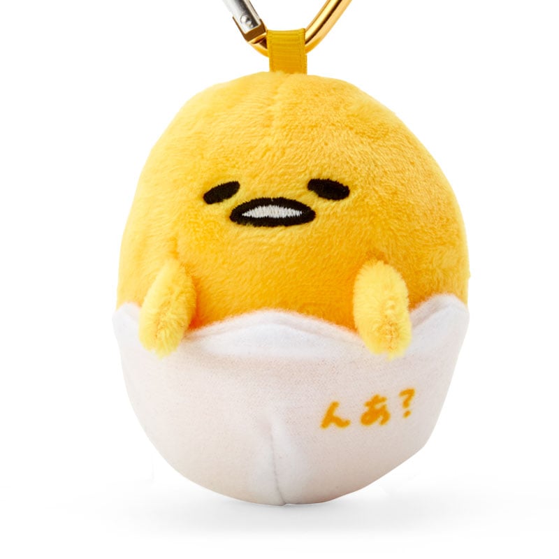 Gudetama plush resting on a notebook, styled for a kawaii desk accessory.