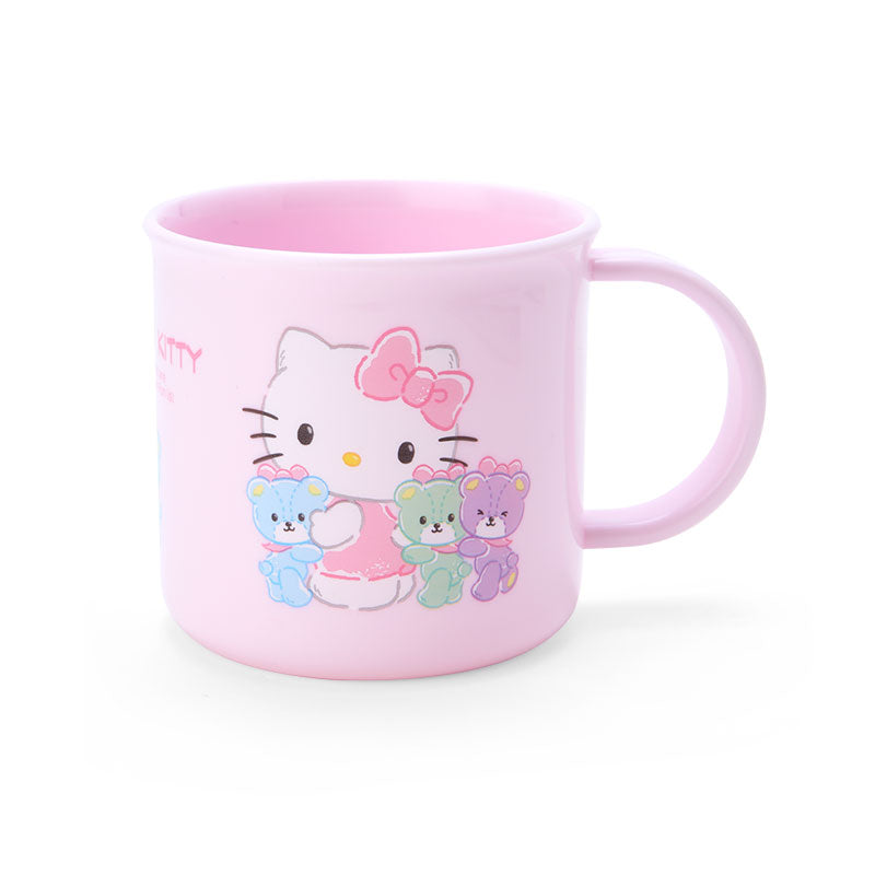 Front view of Hello Kitty mug placed next to a bento box lunch set – pink plastic coffee cup with curved lip.
