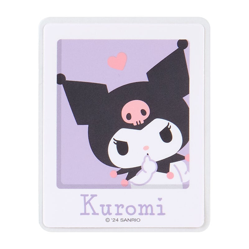 Hand placing a Kuromi decal on a laptop keyboard