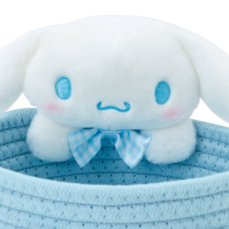Mini mascot sitting atop the woven laundry basket in multi-color