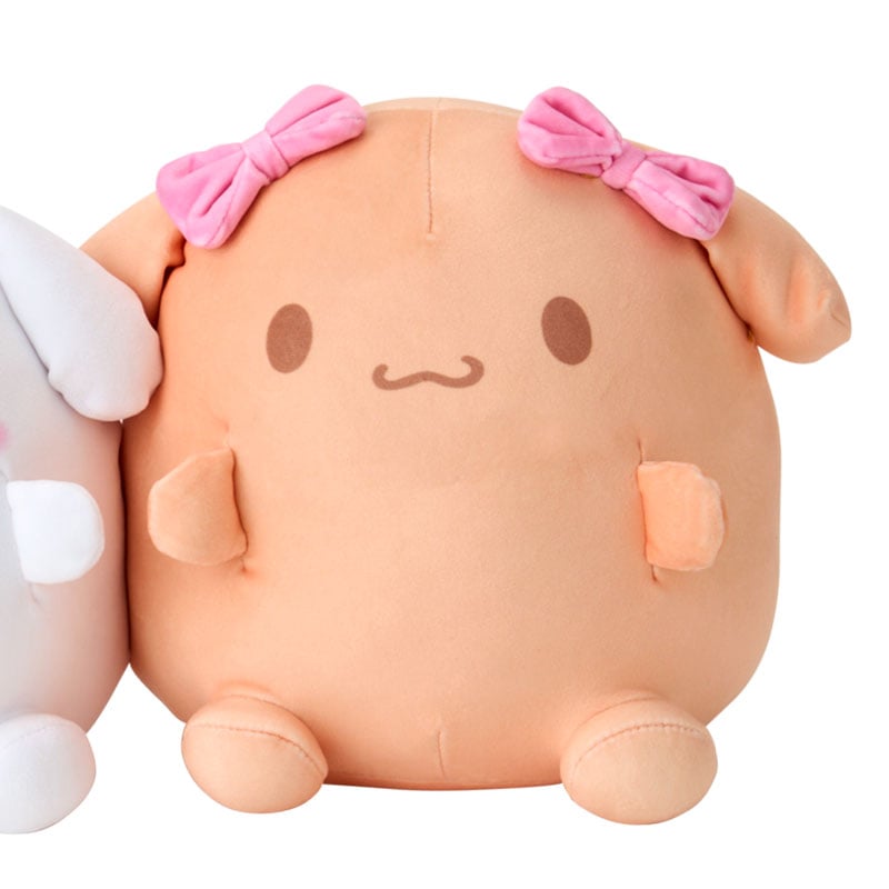 Front view of large cinnamoroll plush and mocha pillow snapped together on a bed