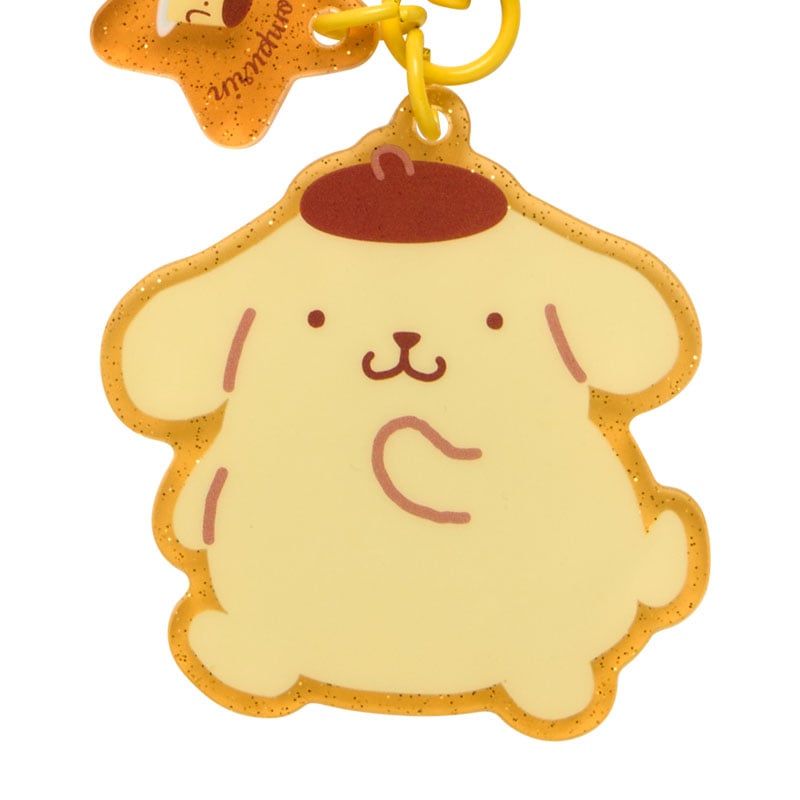 Close-up of Pompompurin adhesive phone charm on a smartphone case, showing cheerful design